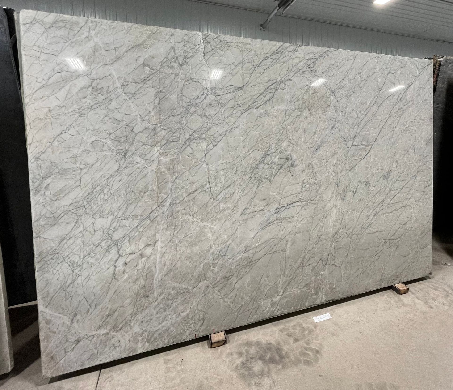 A large white marble slab is sitting on top of a cement floor.
