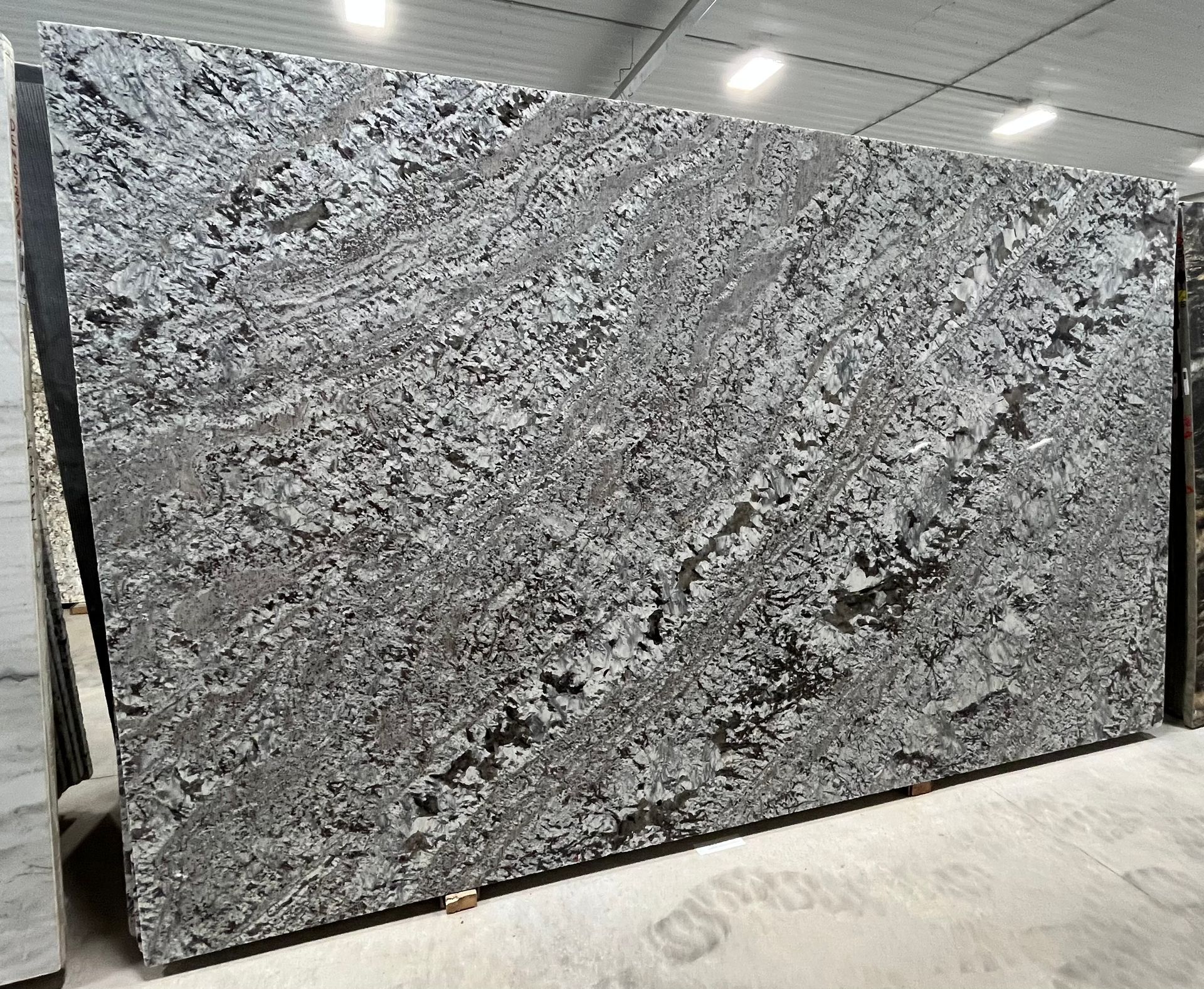 A large gray granite slab is sitting in a warehouse.