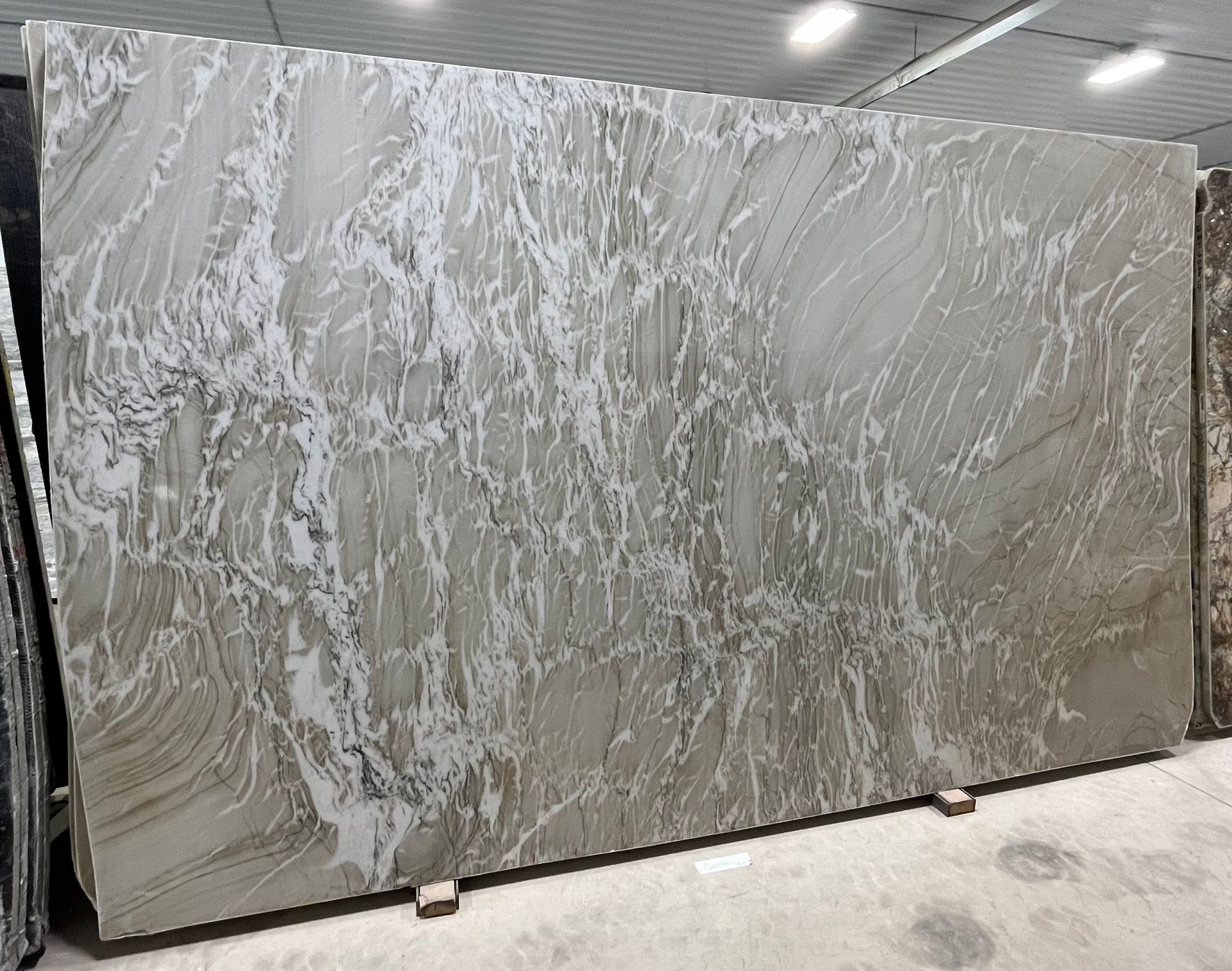 A large slab of marble is sitting on the ground in a warehouse.
