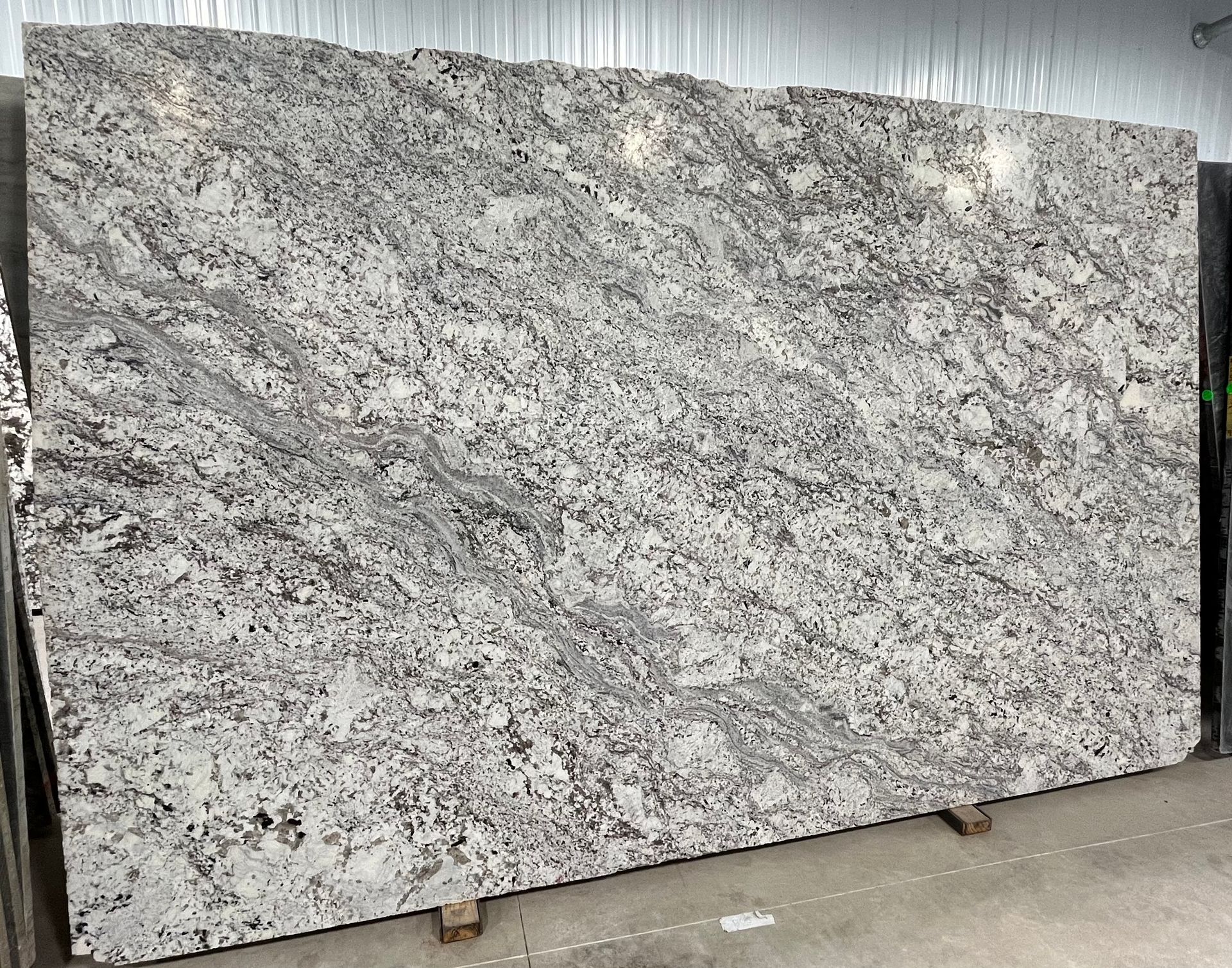 A large white granite slab is sitting on top of a cement floor.