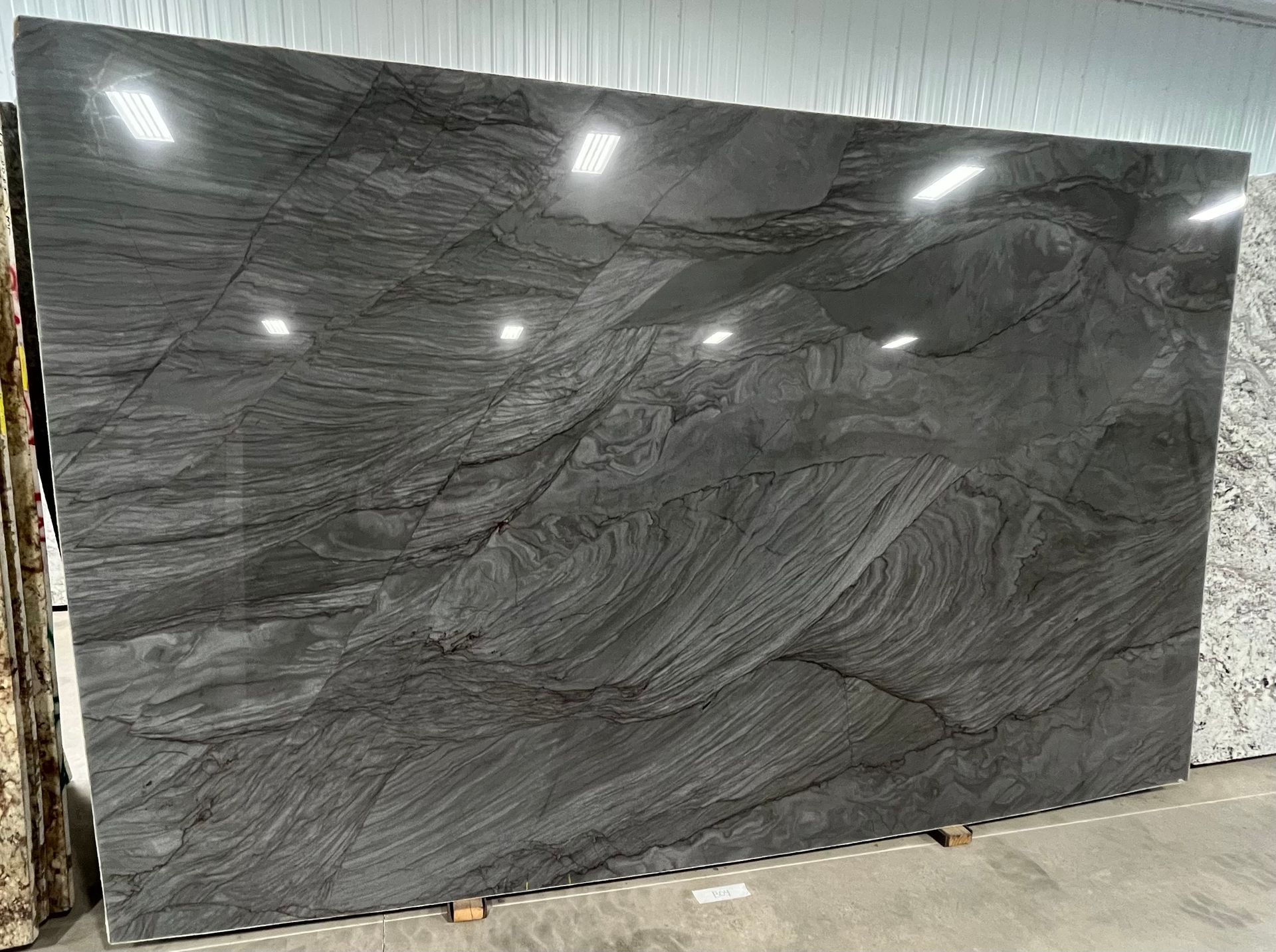A large gray granite slab is sitting in a warehouse.