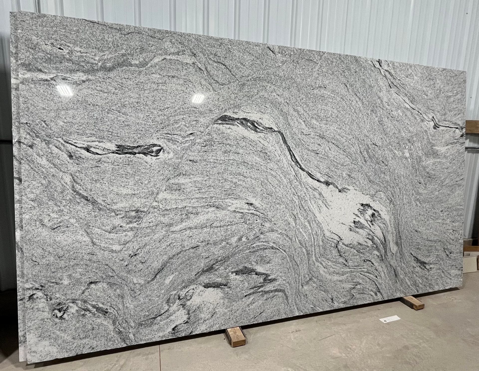 A large white granite slab is sitting on top of a cement floor in a warehouse.