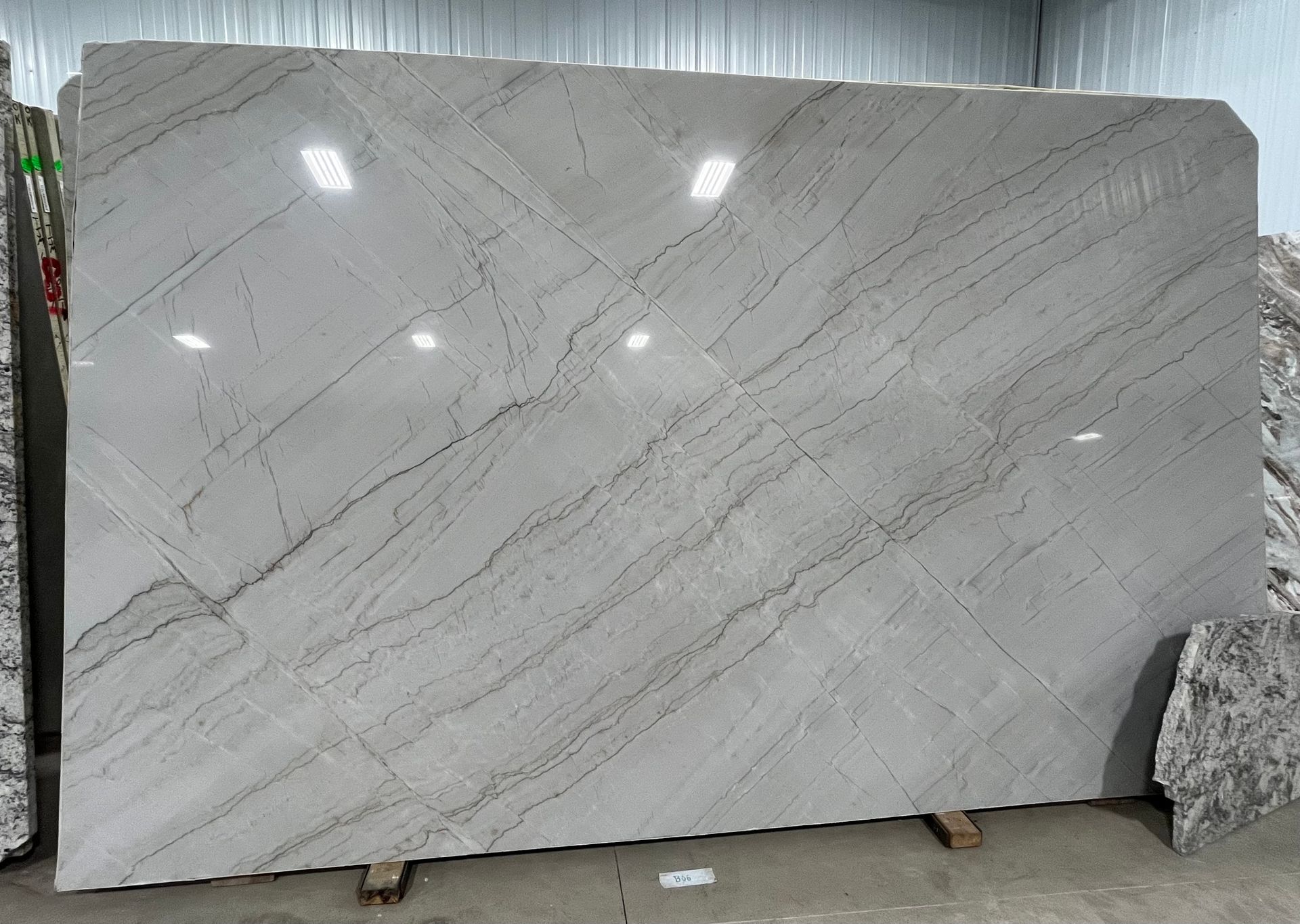 Large white marble slab with gray veining displayed upright in a warehouse-like setting
