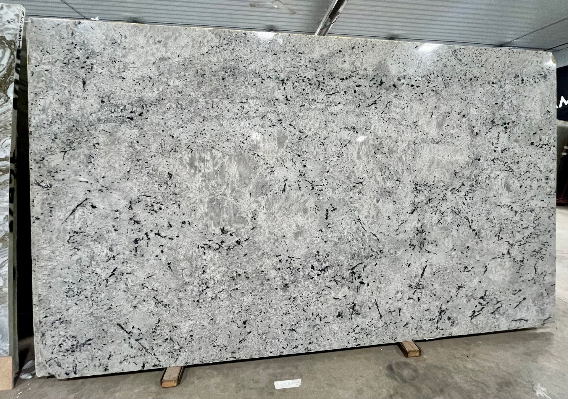 Large white-and-gray speckled stone slab standing upright in an industrial warehouse setting