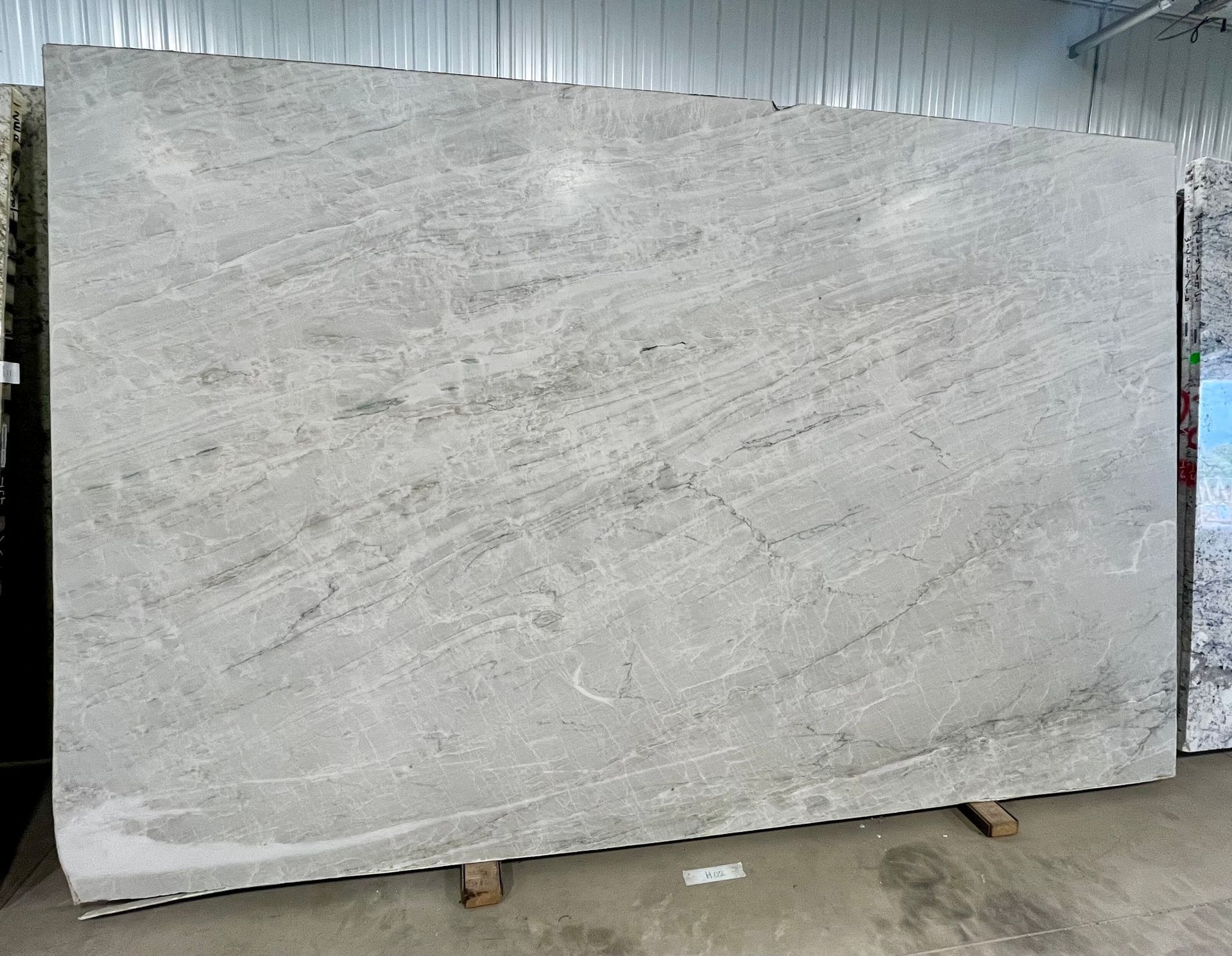 Large light-gray marble slab standing upright in a warehouse-like setting