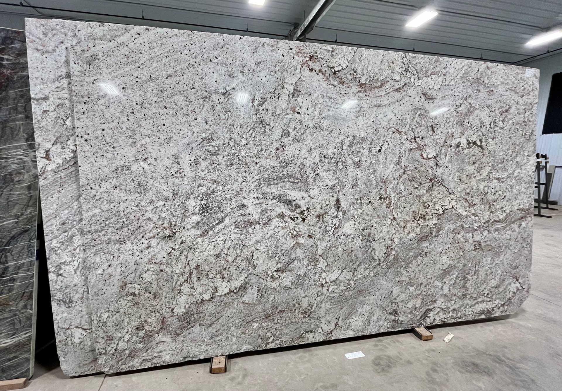 Large gray speckled granite slab standing upright in a warehouse or stone yard