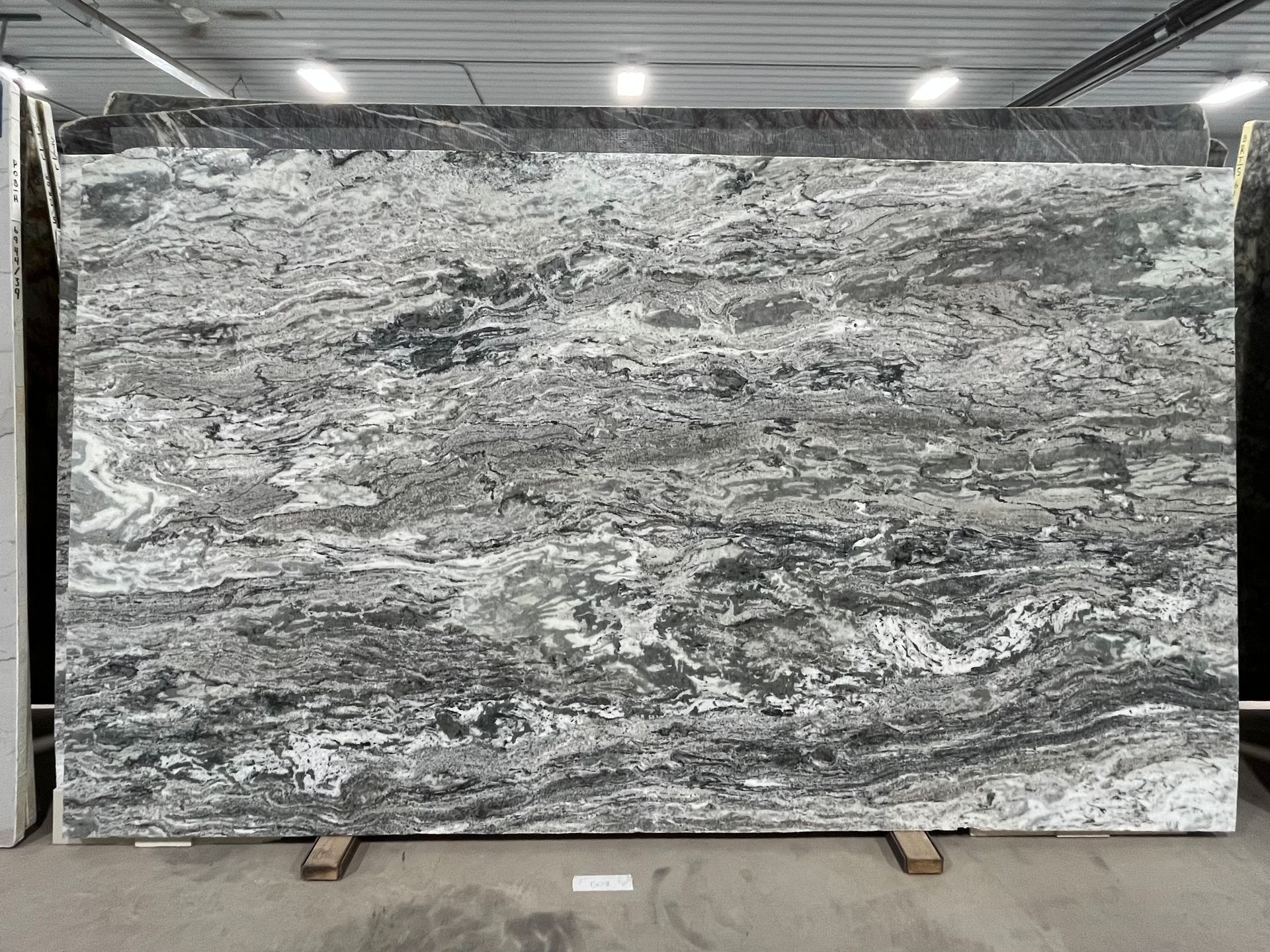 A large, rectangular slab of polished granite featuring a swirling, marbled pattern of black, gray, and white veining.