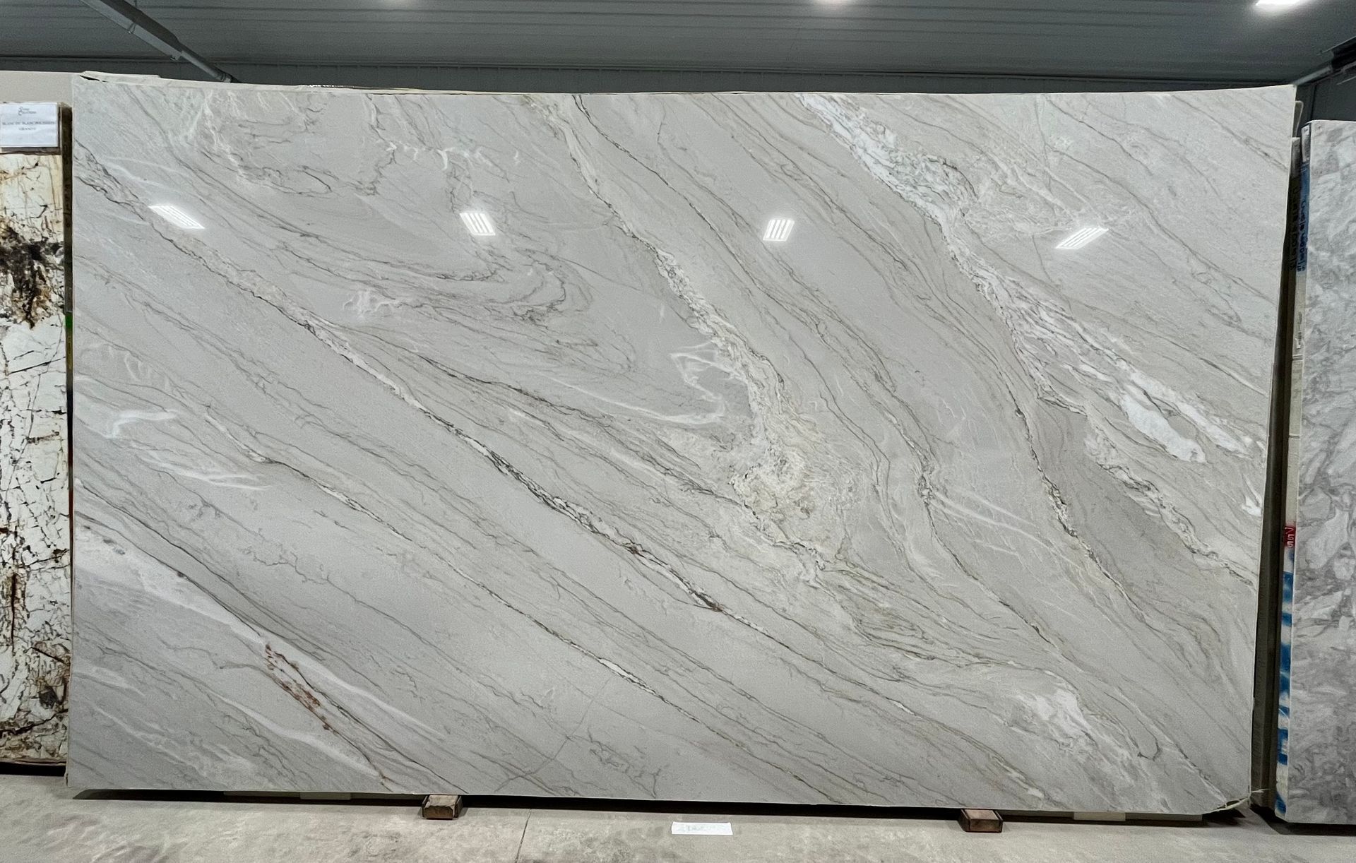 A large rectangular slab of light gray granite with swirling, diagonal veins of darker gray and white.