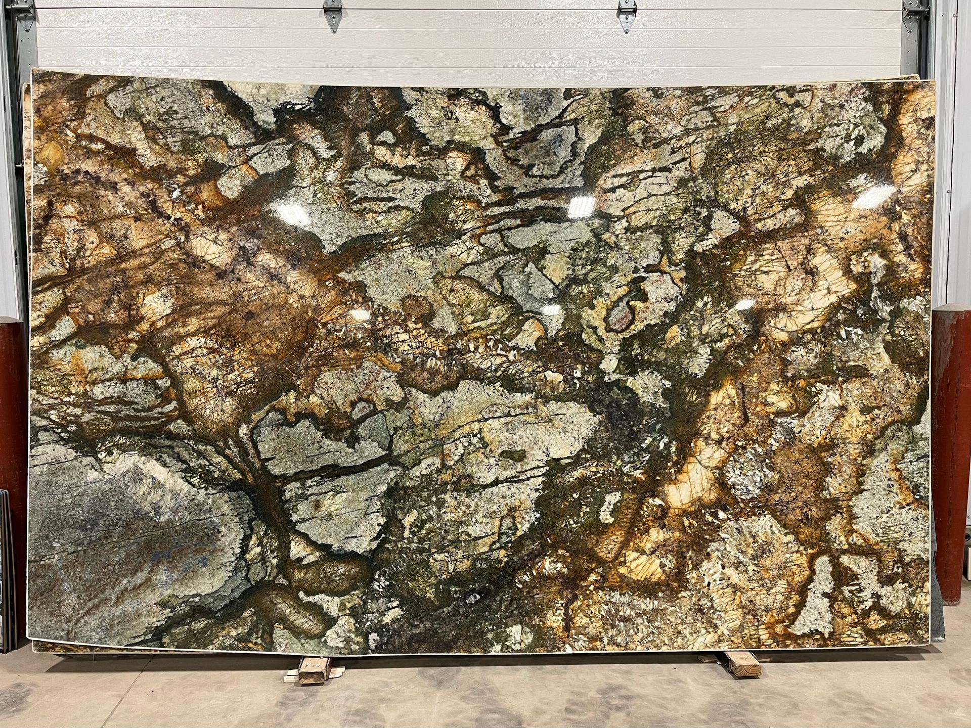 A large, polished slab of granite with an intricate, swirling pattern of tan, gold, dark brown, and black veins.