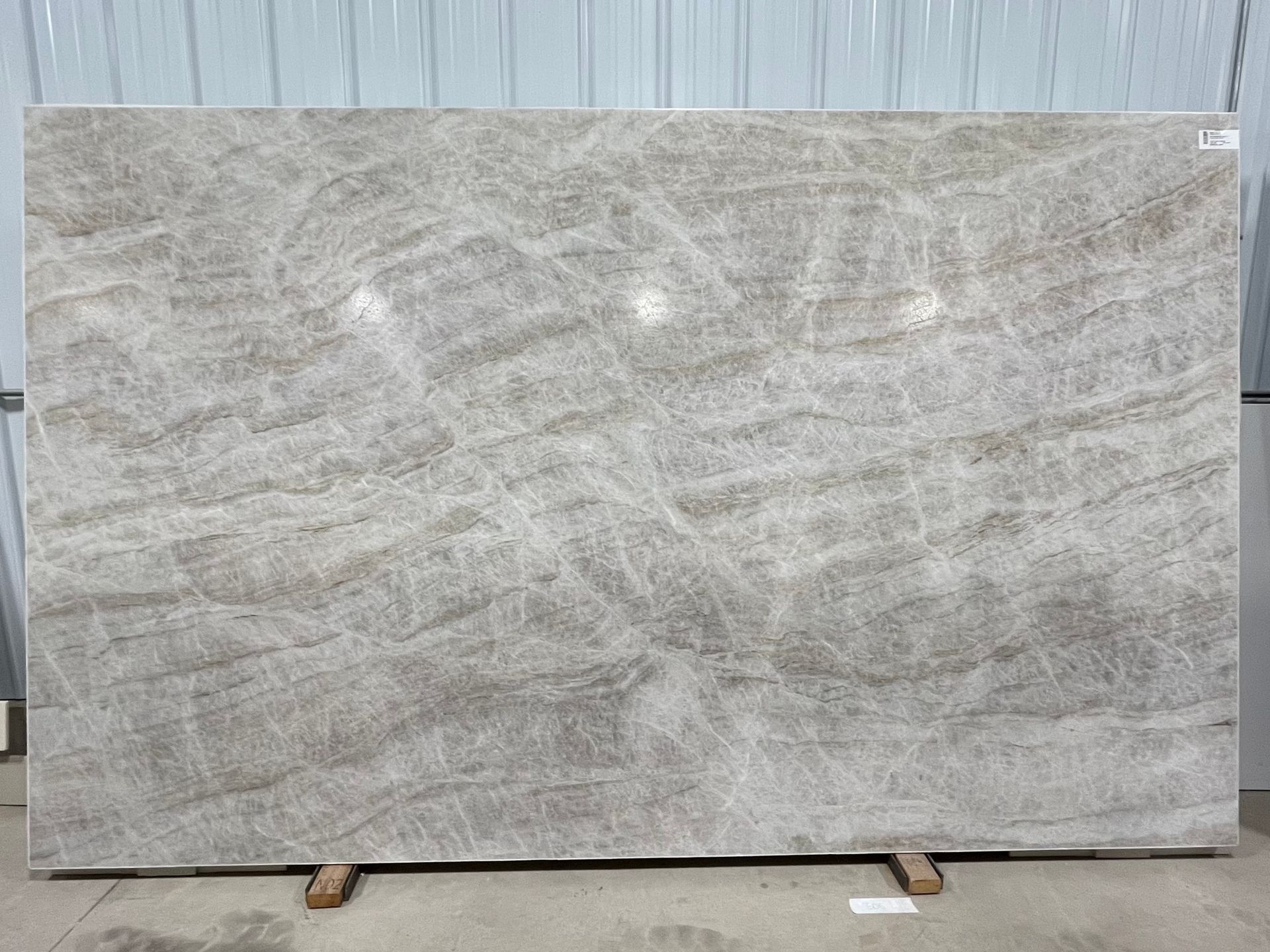 A large slab of light grey and beige marble with horizontal, wavy patterns and fine, textured veining.