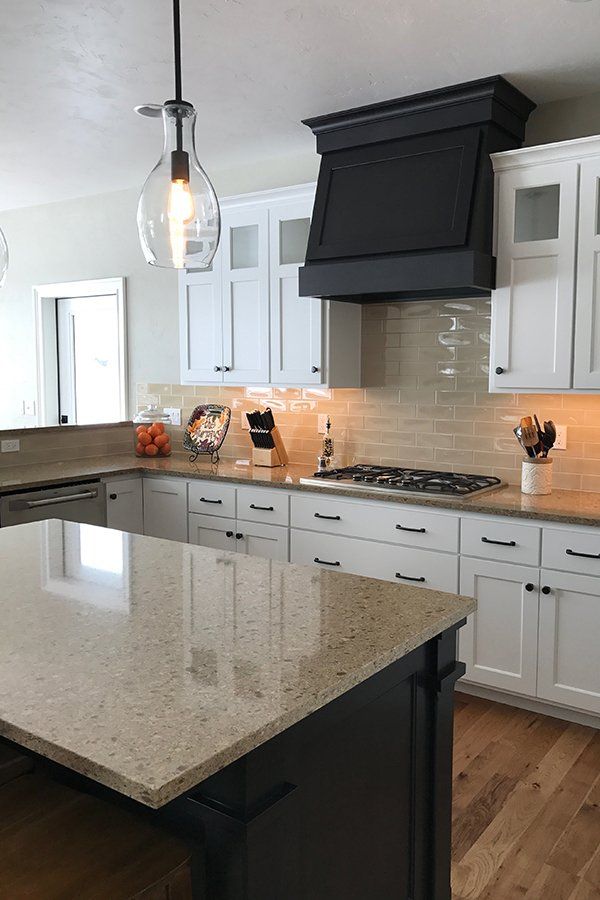 A kitchen with white cabinets , granite counter tops , a stove and a hood.