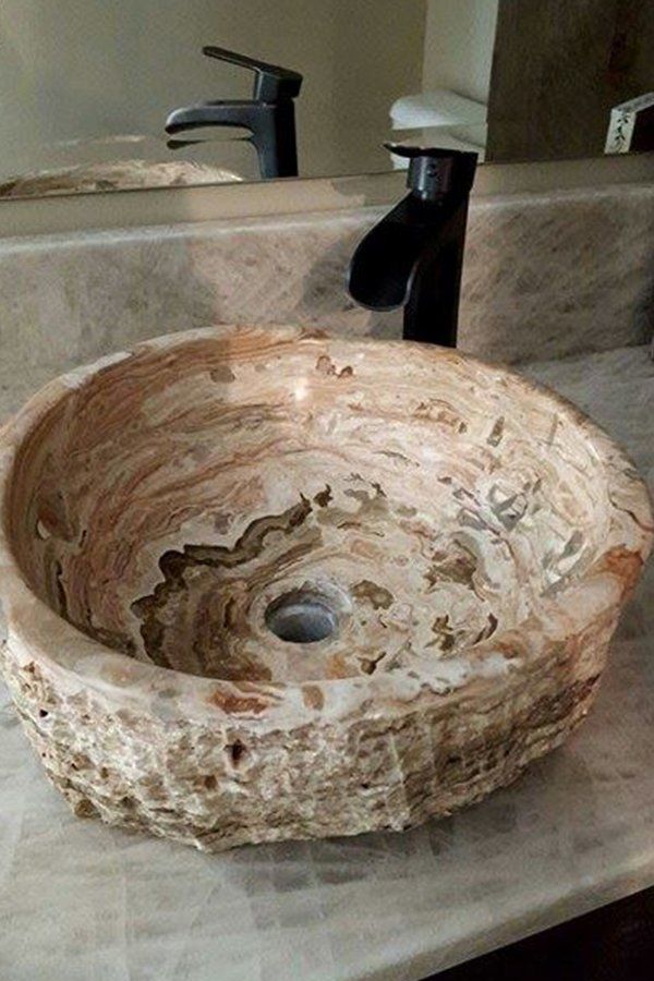 A bathroom sink is sitting on a counter next to a mirror.
