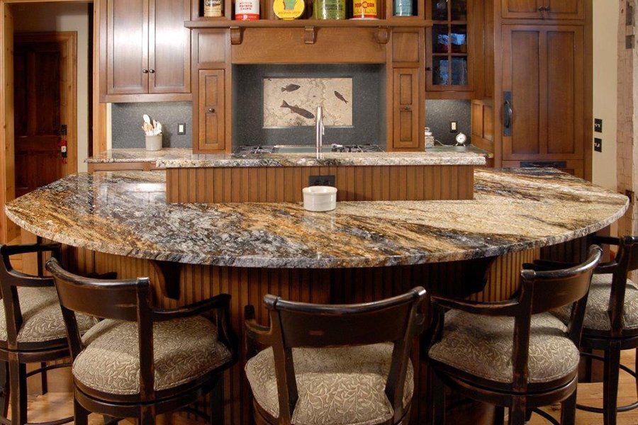 A kitchen with a large granite counter top and chairs