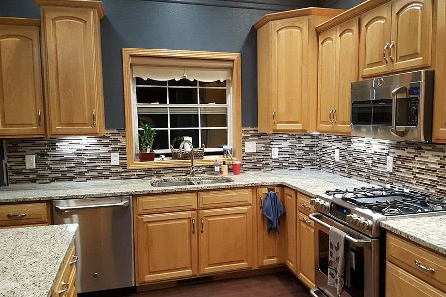 A kitchen with wooden cabinets , stainless steel appliances , granite counter tops and a window.