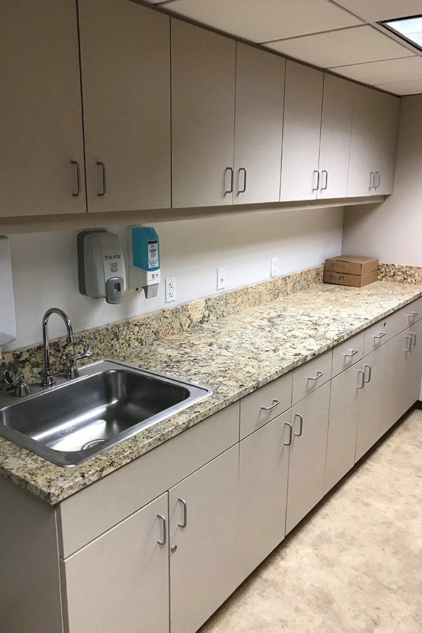 A kitchen with a sink , cabinets and granite counter tops.
