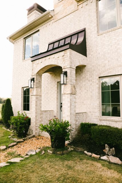 A large white brick house with a porch and a lot of windows
