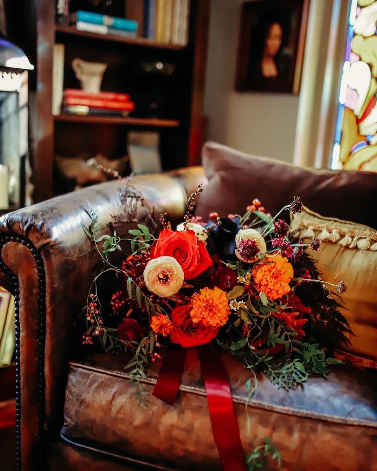 A bouquet of flowers is sitting on a leather couch in a living room.