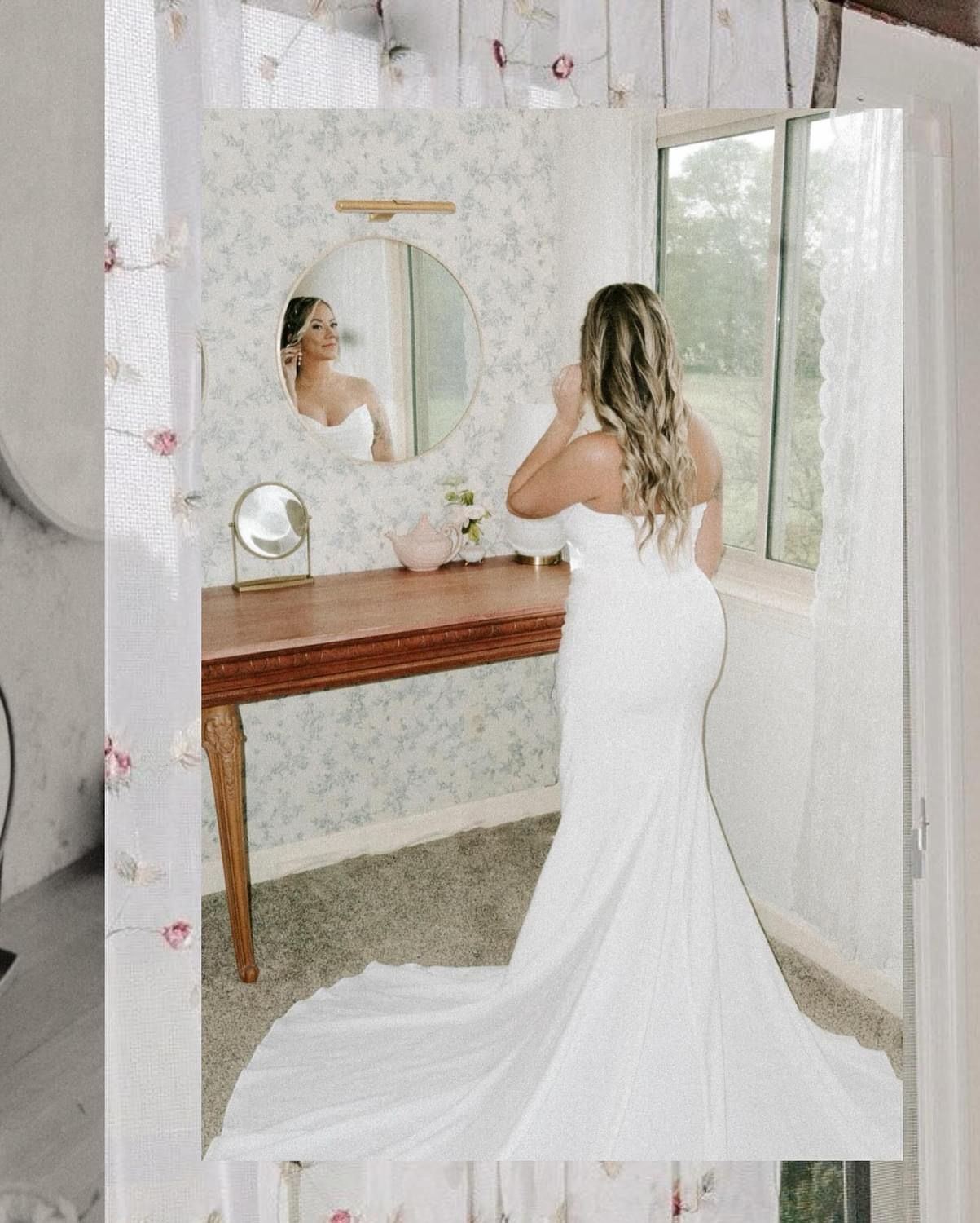 A woman in a white dress is standing in front of a mirror in a room.