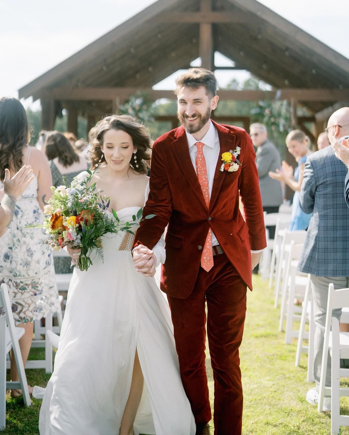 A bride and groom are walking down the aisle at their wedding holding hands.