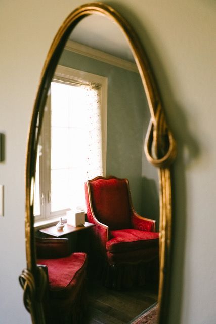 A red chair is reflected in a large mirror