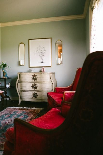 A living room with two red chairs and a dresser.