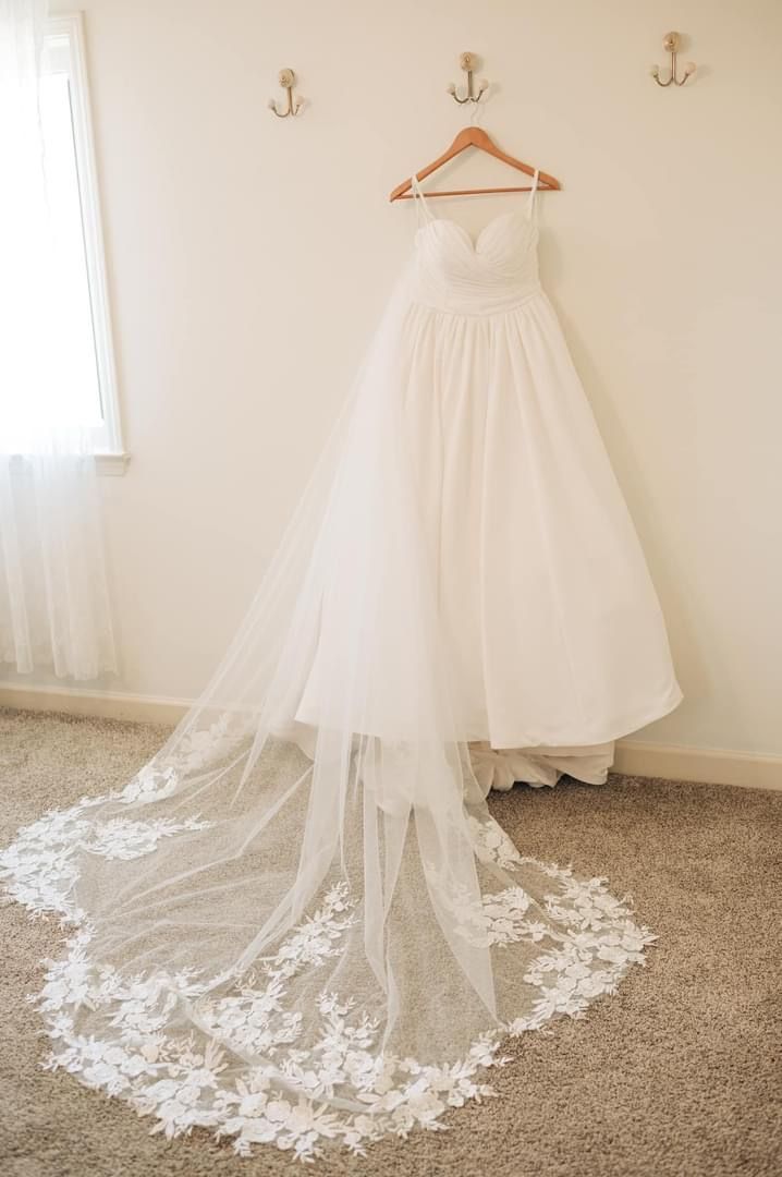 A wedding dress is hanging on a hanger in a room.