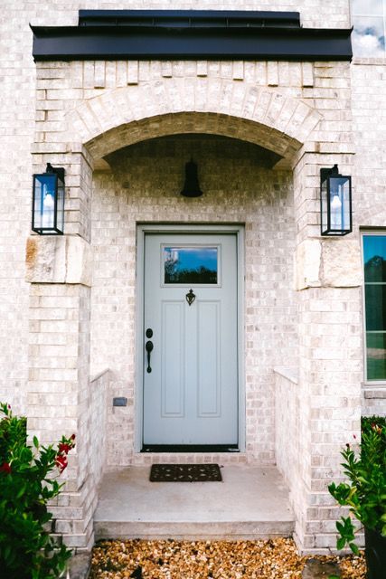 The front door of a white brick house with a blue door