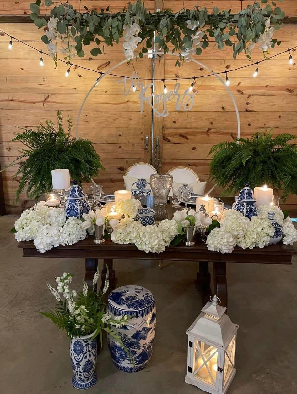A table with flowers and candles on it in front of a wooden wall.