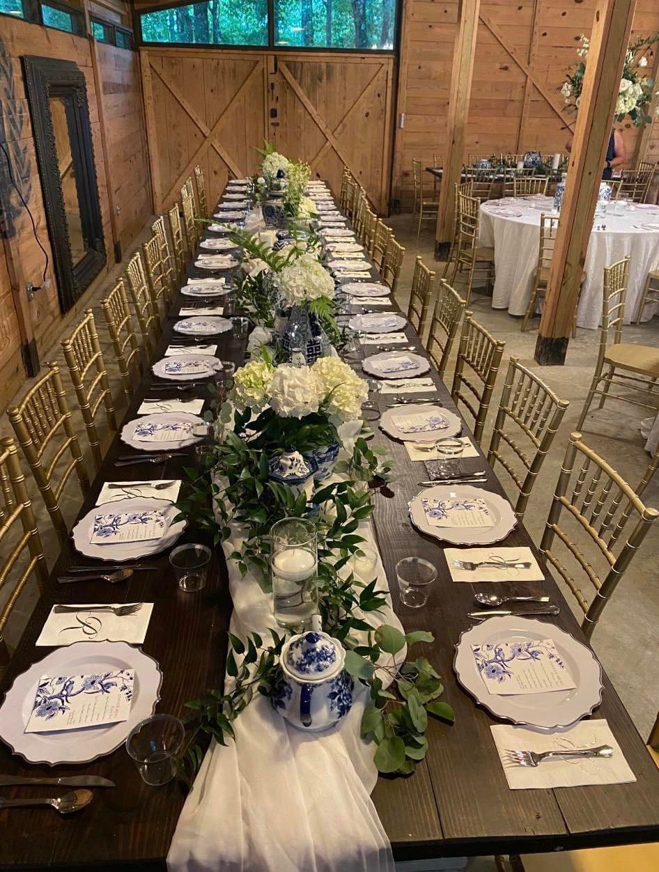 A long table with plates , silverware , and flowers on it.