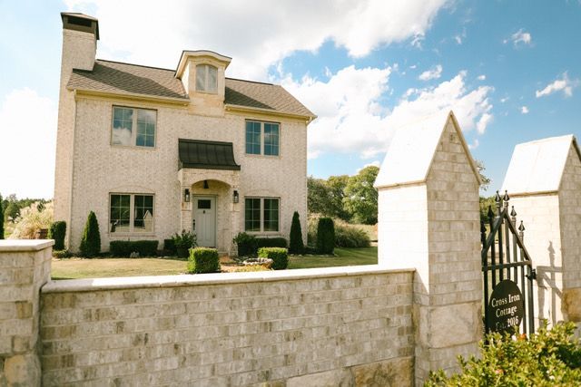 A large white house with a stone wall in front of it