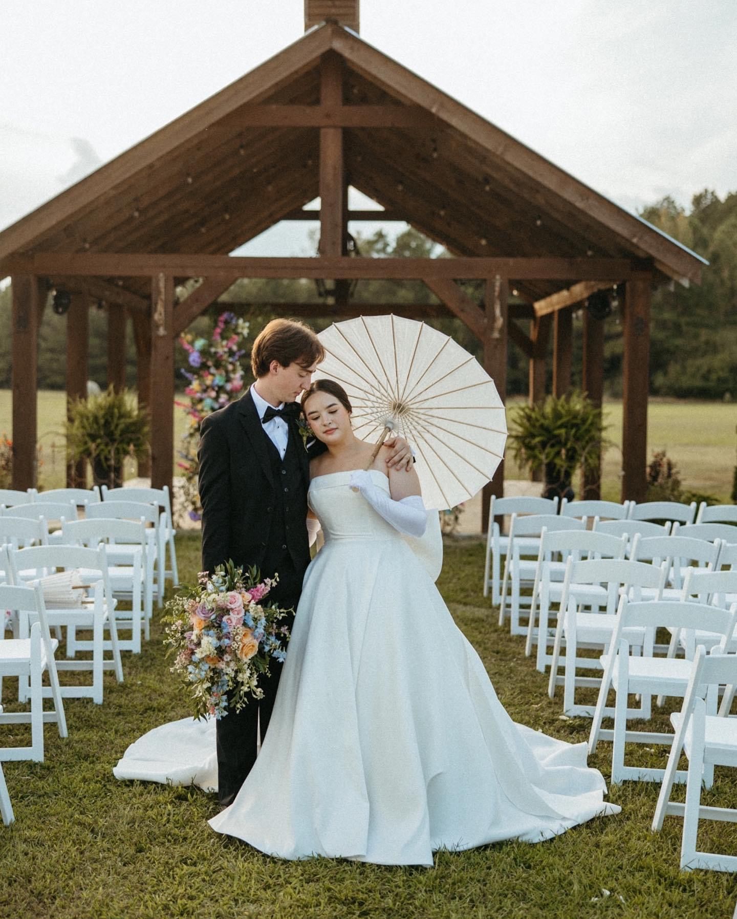 A bride and groom are posing for a picture in front of a gazebo.
