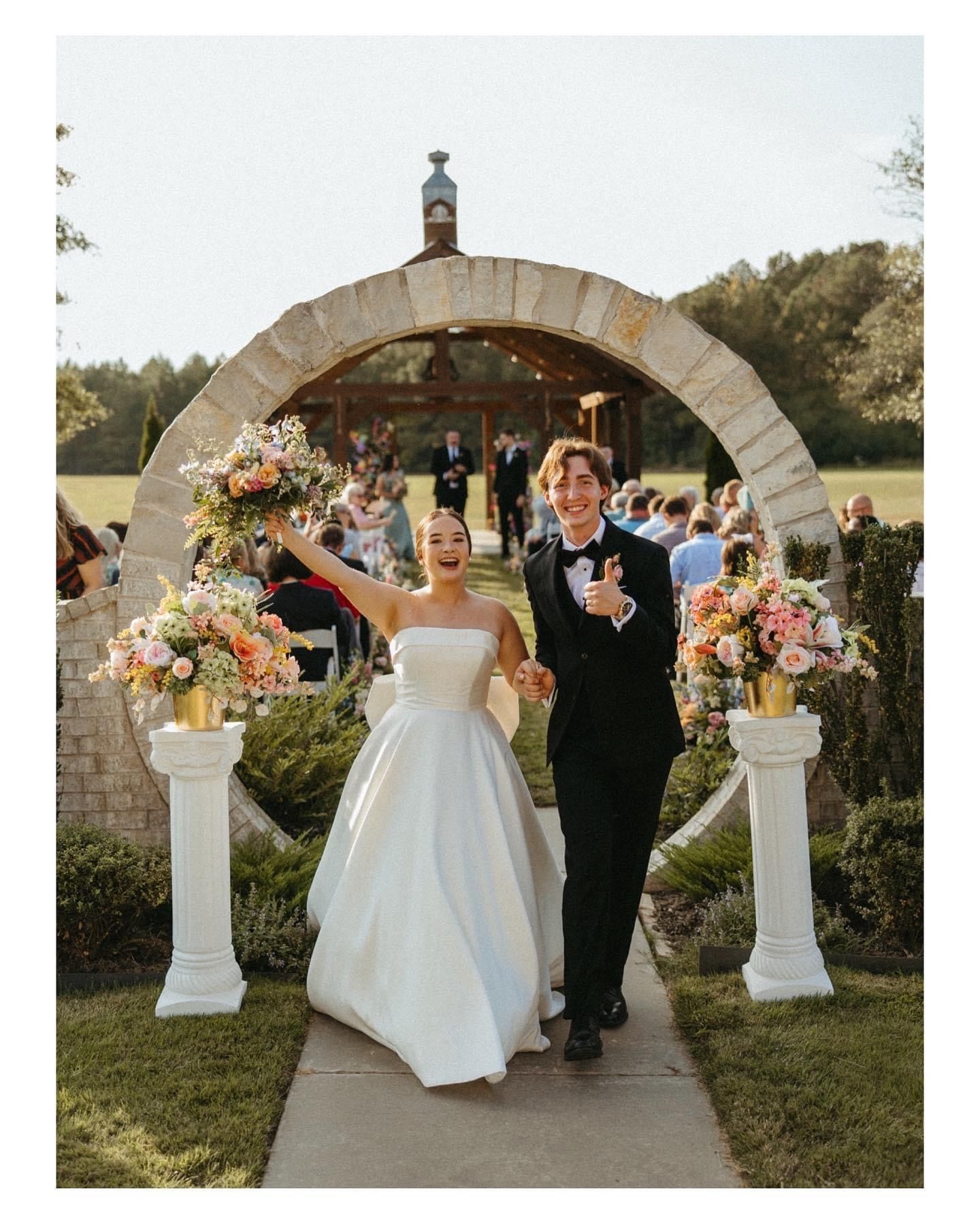 A bride and groom are walking down the aisle at their wedding.