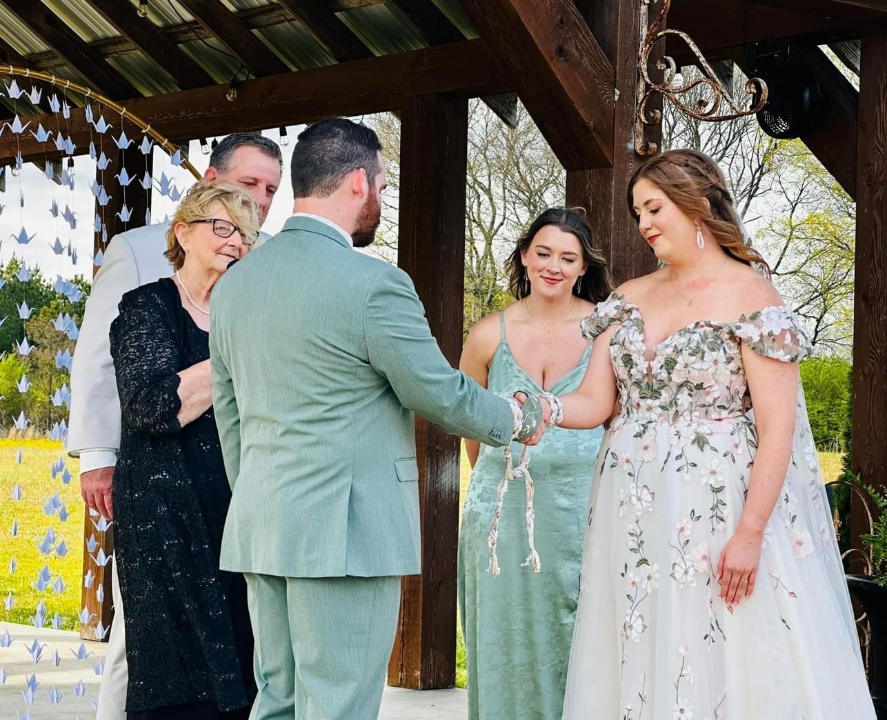 A group of people are standing around a bride and groom at a wedding ceremony.