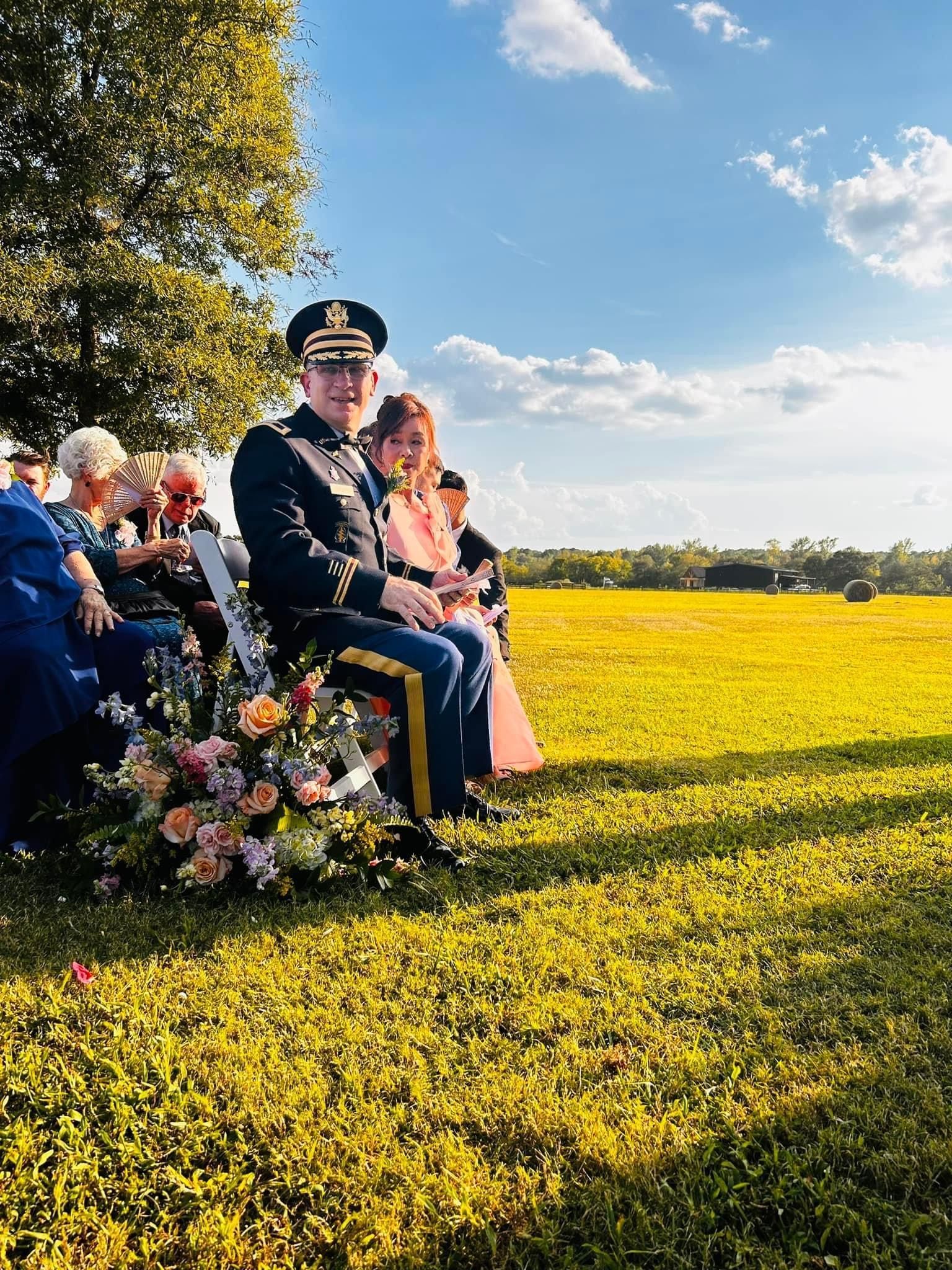 A man in a military uniform is sitting in a chair in a field.