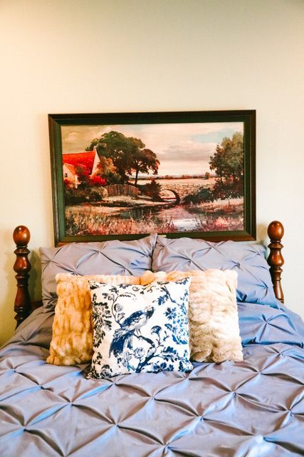 A bed with pillows and a painting on the wall above it