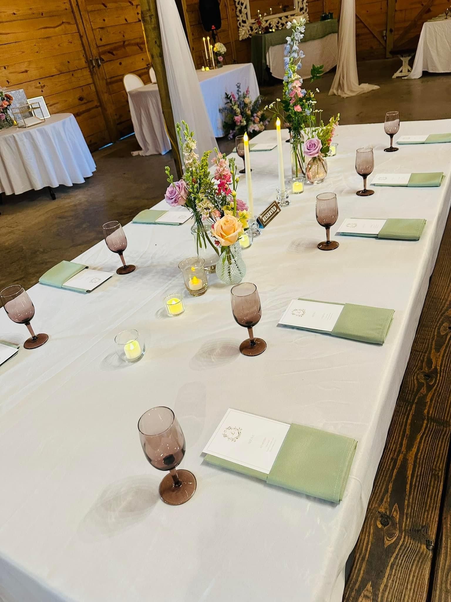 A long table with wine glasses and flowers on it.