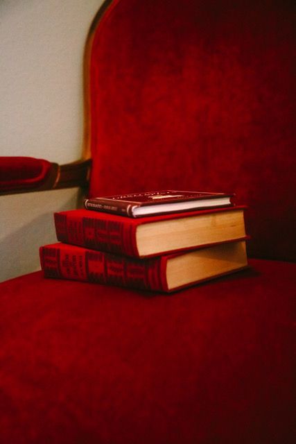 Two books are stacked on top of each other on a red chair.