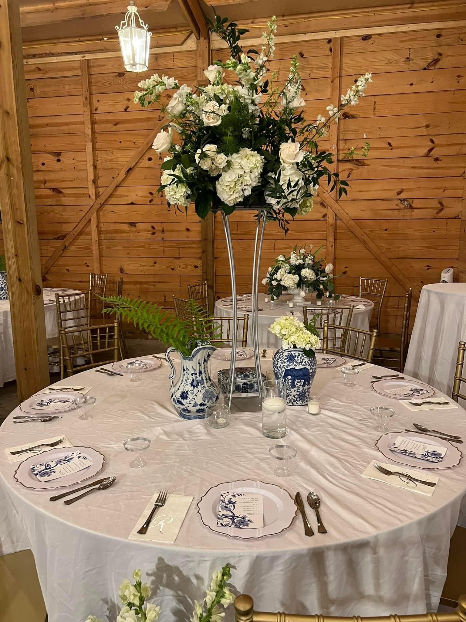 A table set for a wedding reception with a vase of flowers on it.