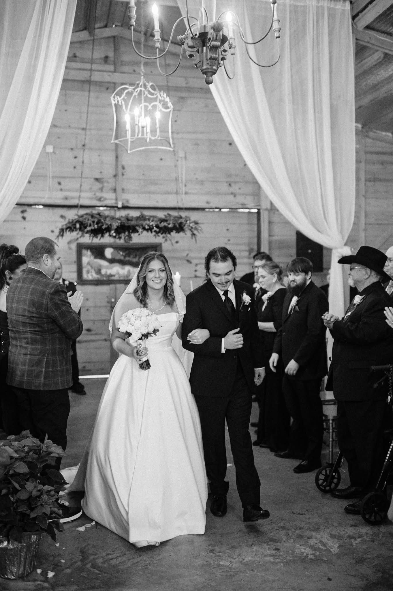 A bride and groom are walking down the aisle at their wedding.