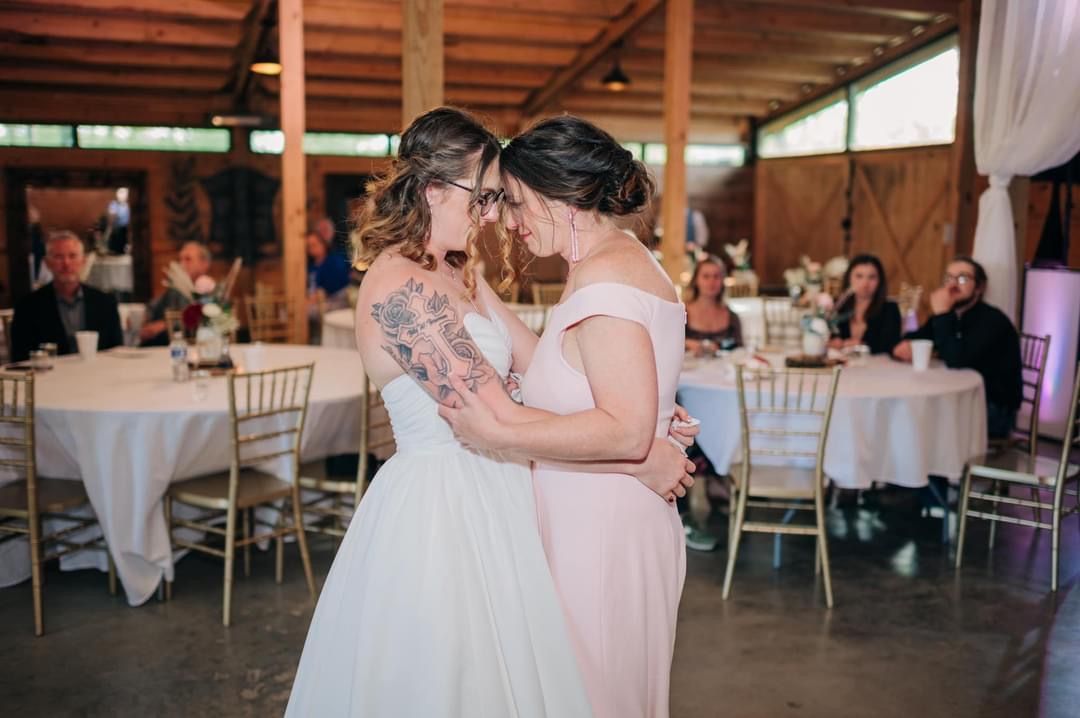 A bride and her bridesmaid are dancing together at their wedding reception.