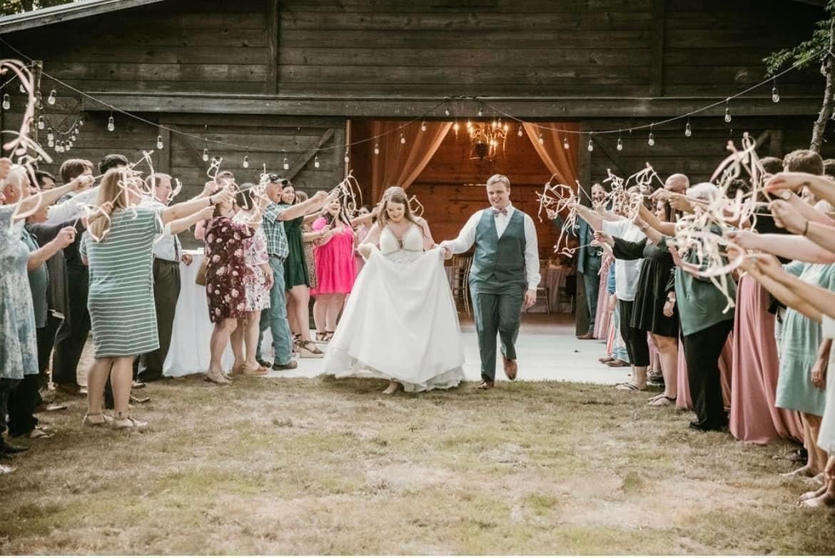 A bride and groom are walking through a crowd of people holding sparklers.