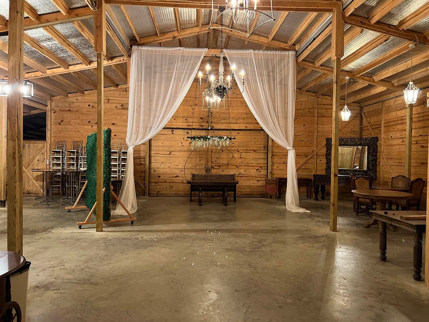 A large wooden barn with tables and chairs and a chandelier.