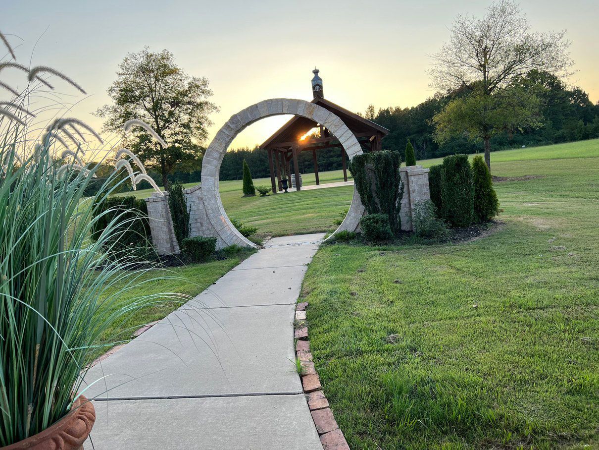 A concrete walkway leading to a gazebo in a park.