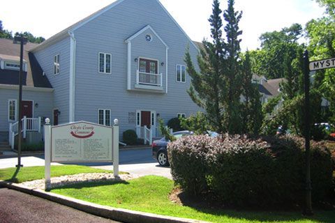 Exterior of Olde Country Commons building with sign on a sunny day.