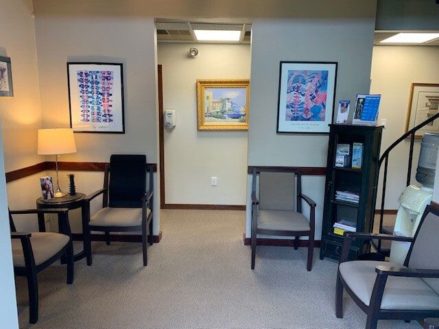 Waiting room with chairs, art, lamp, and water cooler.