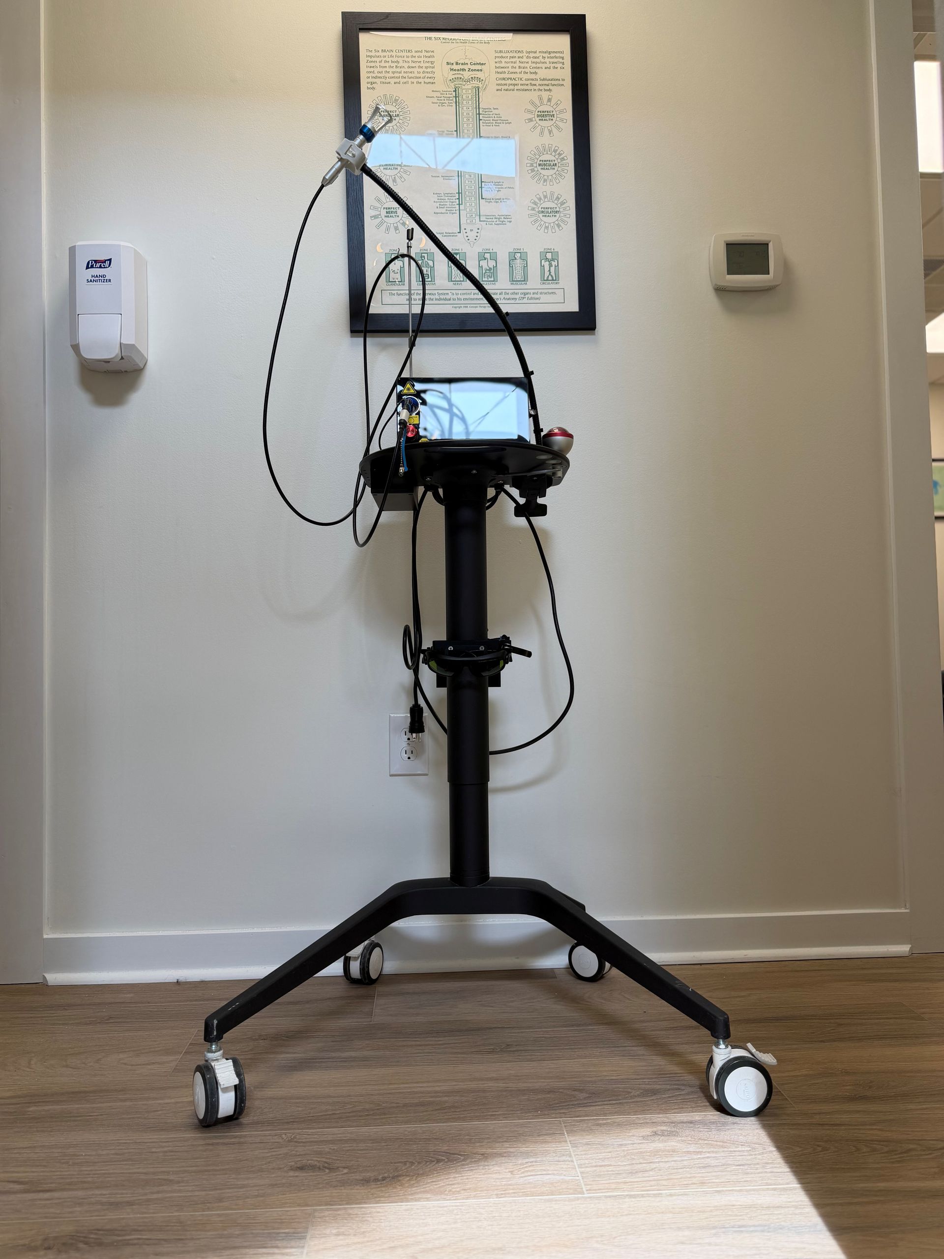 A mobile medical diagnostic device on a rolling stand positioned against a wall in a clinical office setting.