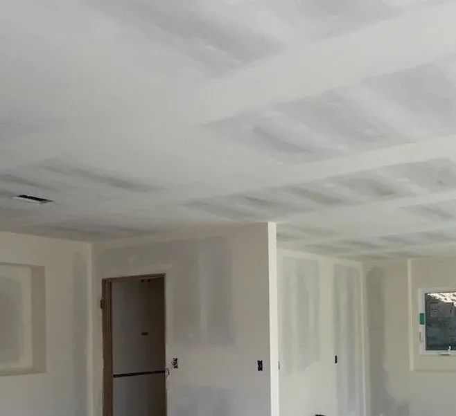 Interior view of a room with drywall on walls and ceiling, unfinished and painted white.