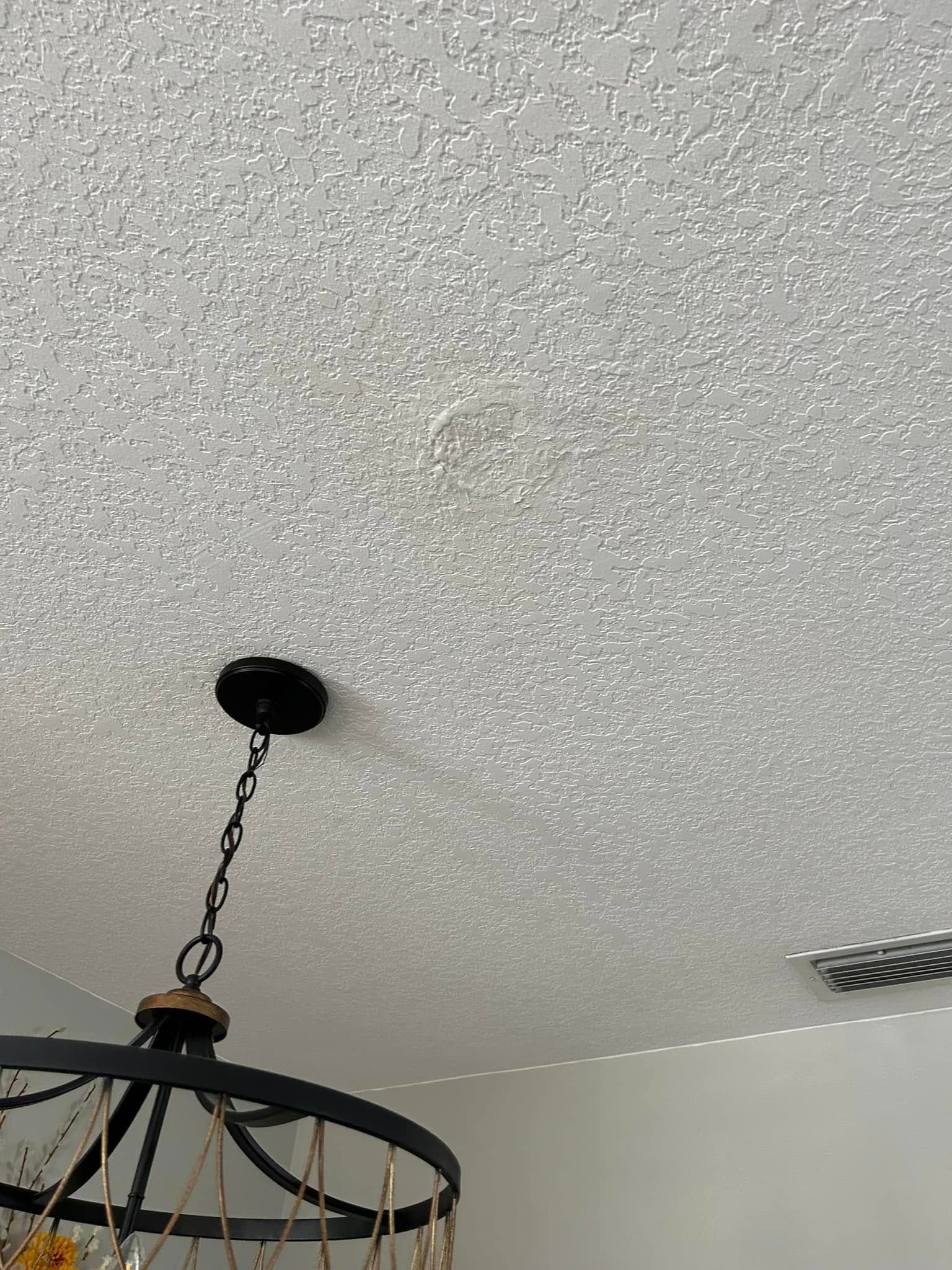 Textured white ceiling with a dark chandelier hanging below.