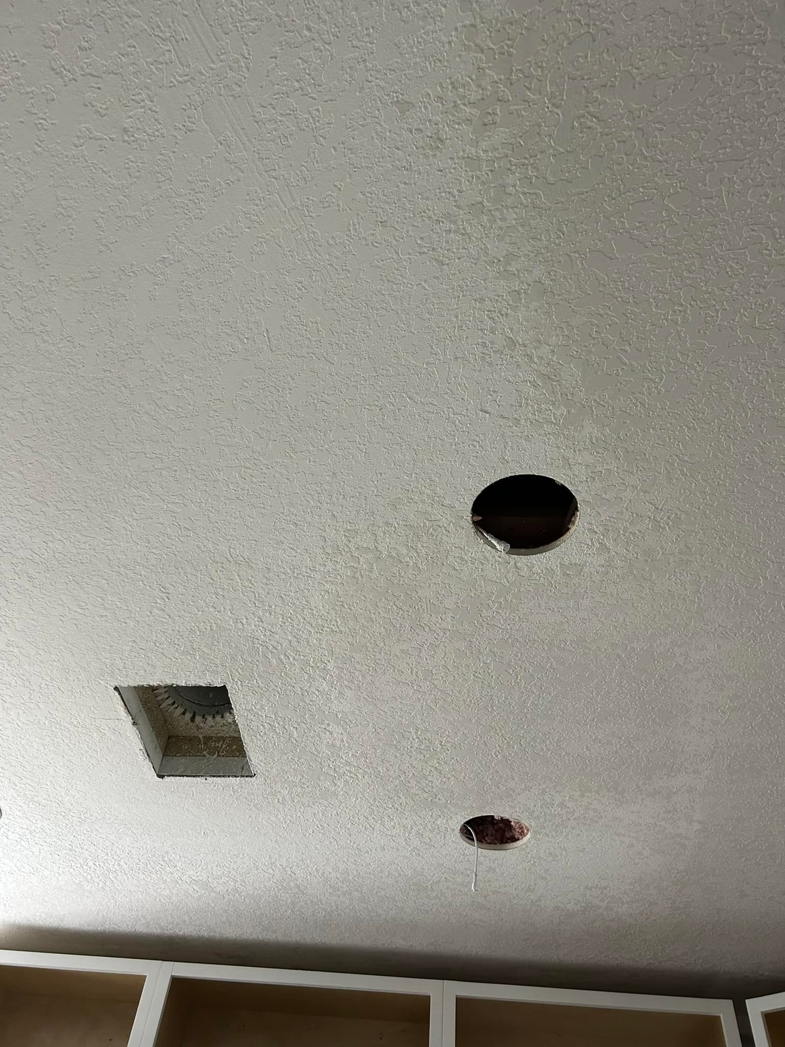 Ceiling with popcorn texture, including one square vent and two circular light openings.