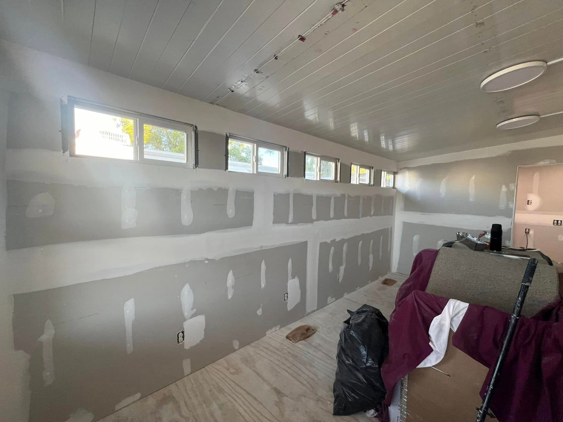 Interior of a room under construction with drywall and small windows along the upper wall.